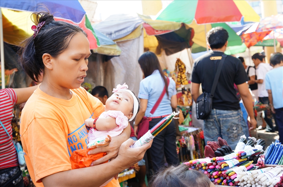 A young mother thoughtfully reads the label on a bundle of colorful candles, which  are said to represent the wishes that will come true when the candles are lit. 