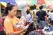 A young mother thoughtfully reads the label on a bundle of colorful candles, which  are said to represent the wishes that will come true when the candles are lit. 