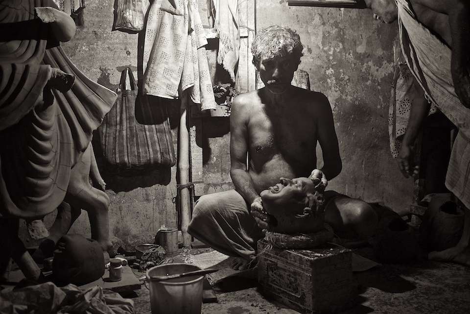 Artist giving the idols head it's final shape in his clay scented shop