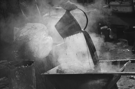 While his co-workers are laying the road, tribhuvan is busy playing with the tar.. Wearing only a single glove and pouring the boiling tar poses a great risk of skin burns. Ignorant of the fact, tribhuvan seems to be enjoying it. 