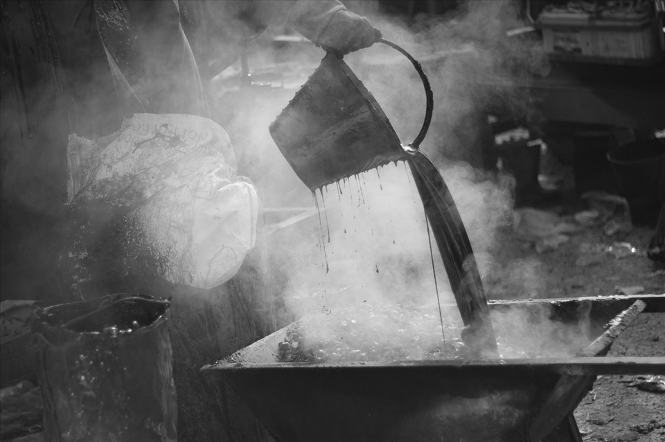 While his co-workers are laying the road, tribhuvan is busy playing with the tar.. Wearing only a single glove and pouring the boiling tar poses a great risk of skin burns. Ignorant of the fact, tribhuvan seems to be enjoying it. 