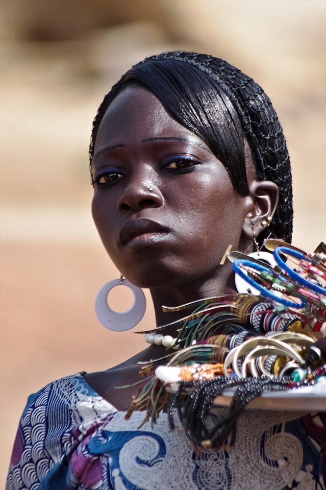 Young woman selling bracelets, her eyes are questioning will she sell enough to buy food for the family