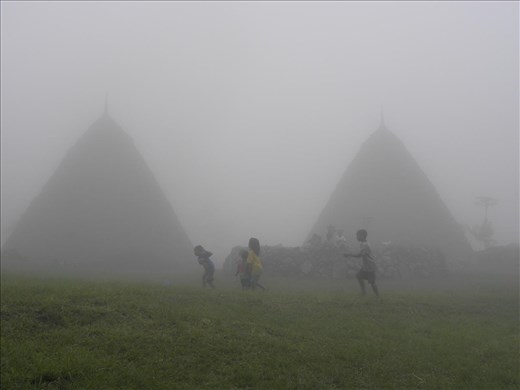 Misty playtime around the central altar in Wae Rebo, a secluded traditional mountain village in West Flores. Since there is no school in the village, the children have to attend the one in the nearest town located 4 hours walking distance from there.