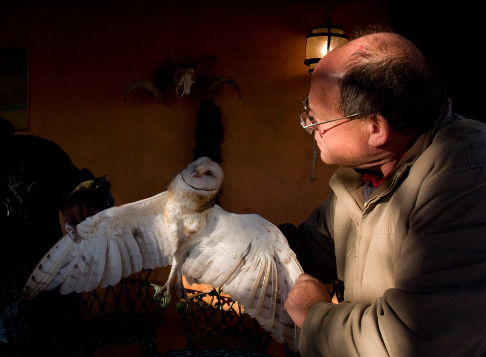 A dead barn owl is inspected by farmer Bob Woody, intrigued by its beauty. Life in the desert can be unforgiving and severe.