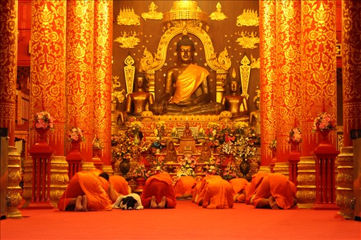 Monks and companion bow to Buddha. Hear no evil, see no evil, speak no evil