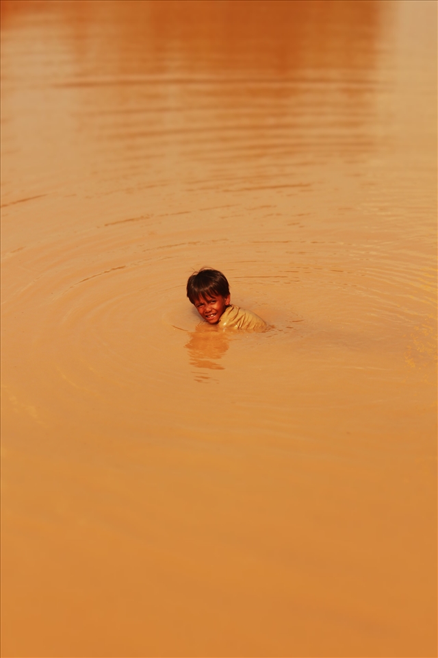 Young boy fishes in dirty lake, he caught a catfish after this photo was taken!