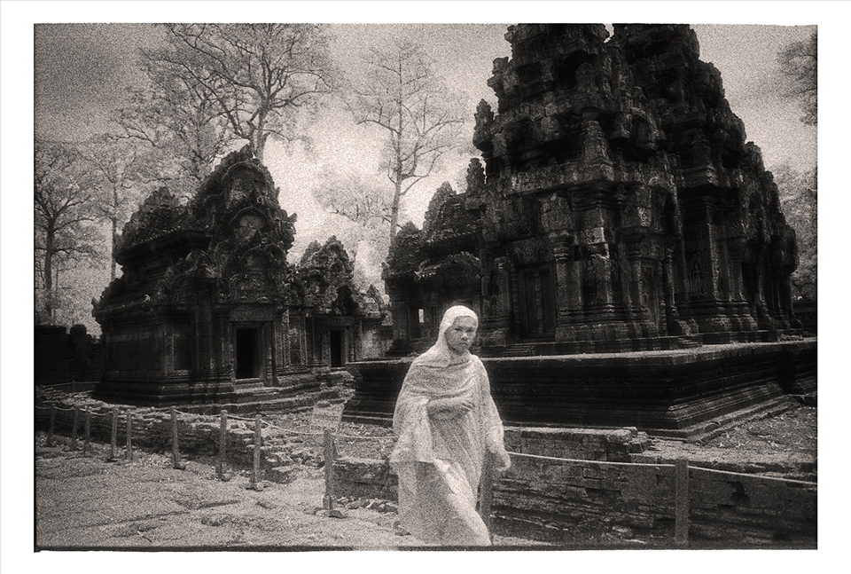 Buddhist monk walks past the ruins of Banteay Srei