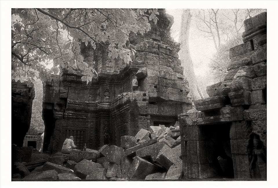 Buddhist nun sits amongst the ruins of Ta Prohm