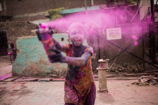 A child plays in the streets spraying paint at anyone daring to cross her path