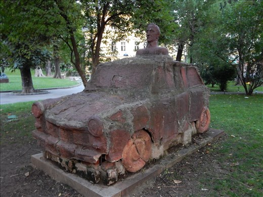 This work of art pays homage to the Trabant which was the most popular car during the communist era and voted the worlds most crappiest car. The Trabant or often referred to as the Trabbi went from 0 to 60 in 21 seconds, was known as a spark plug with a roof, and is an object of playful ridicule. Regardless of all its shortcomings it was used to pick up the Pope when he came to town but the head sticking out of the roof is not the Pope's, it's the artists. 