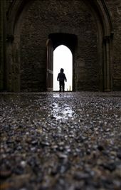 Within the Nave of The Rock of Cashel, a curious young boy stands under an arched doorway, gazing out on to the graveyard. Located in the town of Cashel, South Tipperary, the historic landmark attracts approximately 250,000 visitors per year. : by daniellemerchant, Views[613]