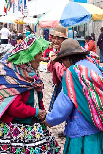 Three local Quechua women stop for a laugh during their market shopping.