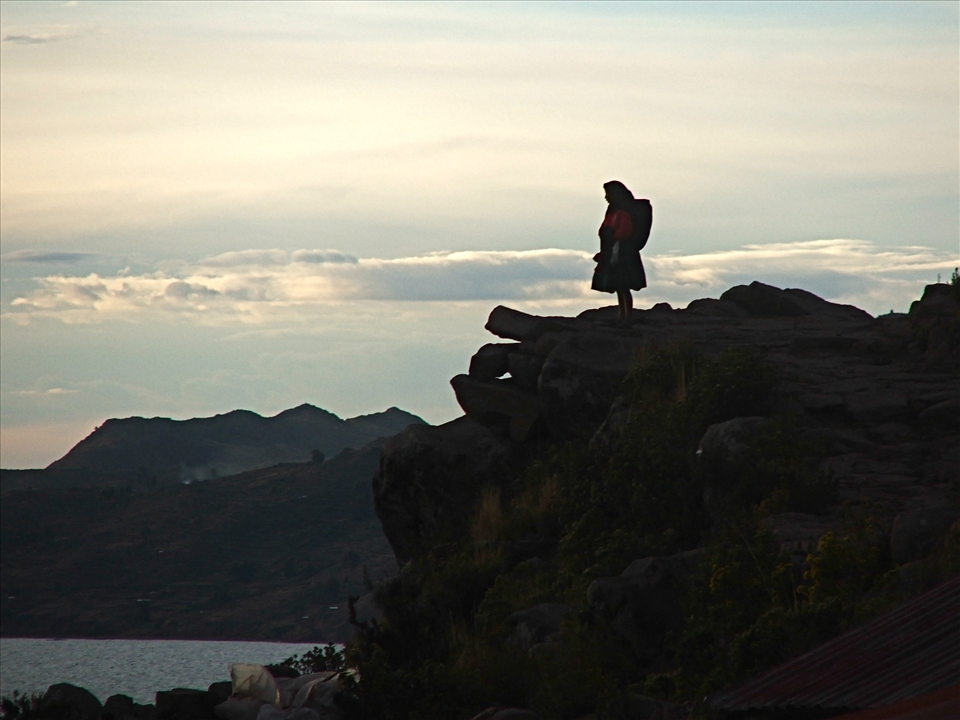 A lady looks out at sunset on Lake Titikaka, the island of Tikelae.