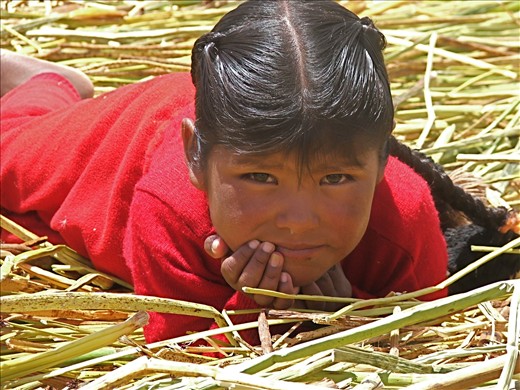 A young girl pierces my camera lens on a reed island on Lake titikaka.