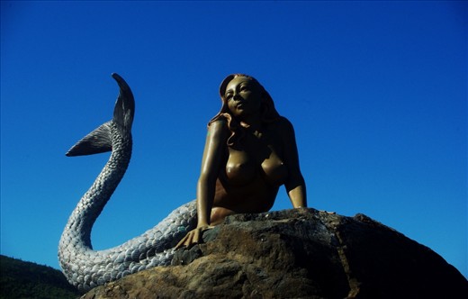 A steel mermaid in the middle of a natural playground.