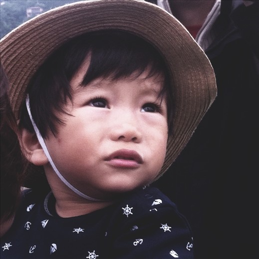 A baby looks up at Mt. Fuji. Although often covered in cloud, is now visible.