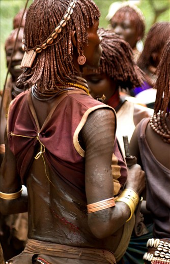 As a women are beaten by men the dance ceremony continues. 