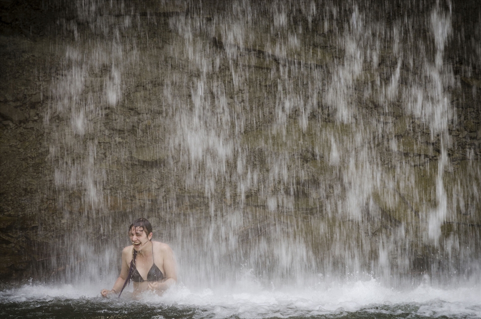 My travel partner enjoying the downpour of a large waterfall.