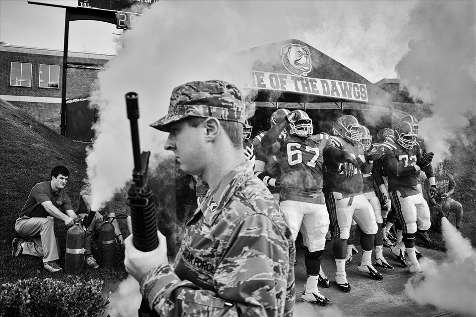 An ROTC stands guard a university football team comes on to play.