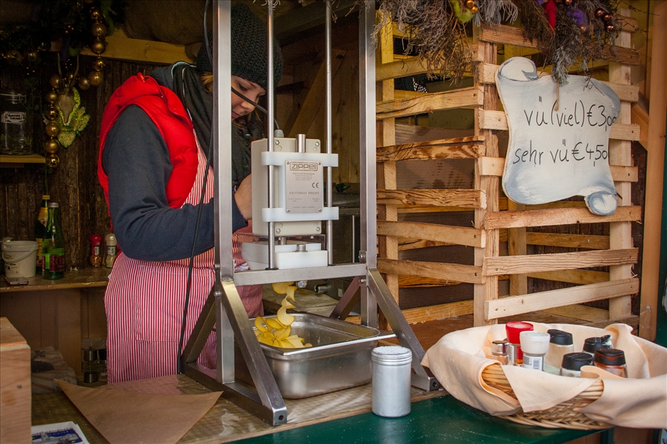For a light lunch I wanted to try a local speciality. This lady is preparing fresh potato chips at one of the Advent Market stalls. The machine she was using was quite intriguing - a fresh, uncooked potato is inserted into an oval hollow and pressed down with the movable piece at the top. It is spun through a series of sharp blades and cut very thinly into a spiral, which falls into the large metal platter below. The whole thing is then deep-fired and put into a paper cone. What I found amusing are the size options mentioned on the plaque on the right: 