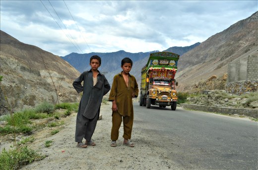 Two young children (local) standing sideby road while truck was coming.