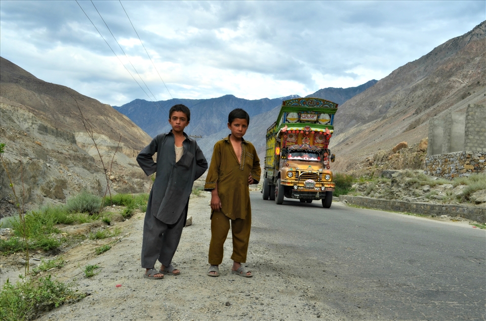 Two young children (local) standing sideby road while truck was coming.