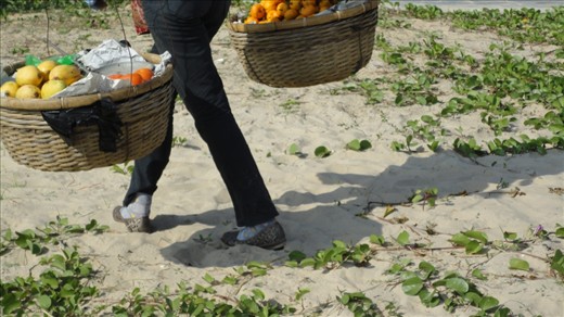 A fruit seller walks the beach trying to sell some fresh fruit in the popular resort of Sanya, an island off the South Coast of China (popular with the new rich Chinese and Russian tourists)