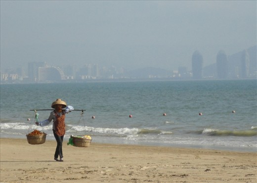 A fruit seller on the beach in Sanya, an island off the South Coast of China with the new skyscrapers ever present in the background.