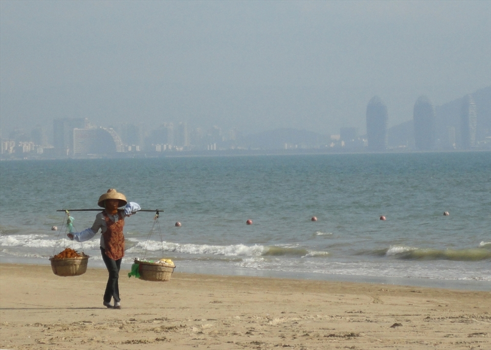 A fruit seller on the beach in Sanya, an island off the South Coast of China with the new skyscrapers ever present in the background.