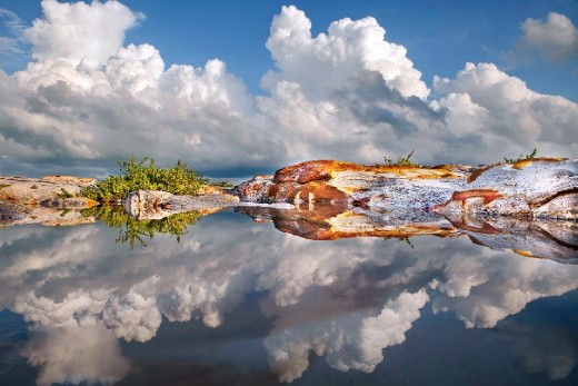 Darwin's foreshore is partially covered by the most amazing and colorful rock formations you can imagine.  It just adds to the colors of the ocean and the skies experienced here in the top end.
But when I took this photo of a rock pool within the rock formation , I realised that the reflection made these amazing figures within the photo.
This photo is a challenge and you can get lost in it. 
 But first just look into it, then look even deeper into it....look for the faces.
Then turn your head left and look at the faces that way.
Then turn your head and look for the perfectly reflected kangaroo and other faces created by the rocks.
It is almost like a totem pole with many stories told on it.