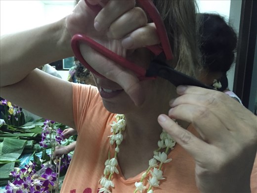 Dina hacking off a chunk of hair, with very dull scissors, to add to the Khoy Lom. 