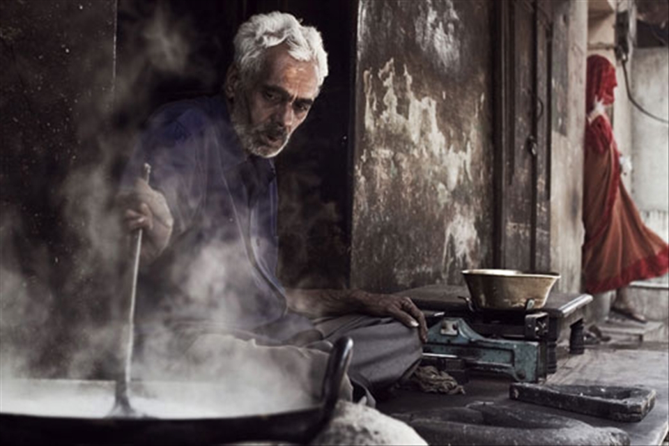 Man cooking on the streets while life goes on
