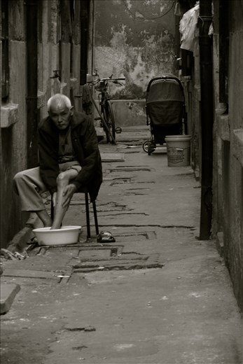 A lonely man at the end of a very long street waiting for his wife to come back.