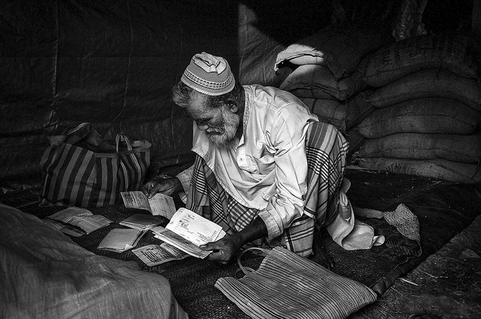 Moijal Seikh, 62, looks at identification documents to ensure even distribution of limited food grains across residents in Dotma. His tent acts as the storage house for grains where he lives with his family.  The government provided ration for 21 days in August. Five months later, food shortage is still one of the major issues. Other basic needs are not current priorities. 