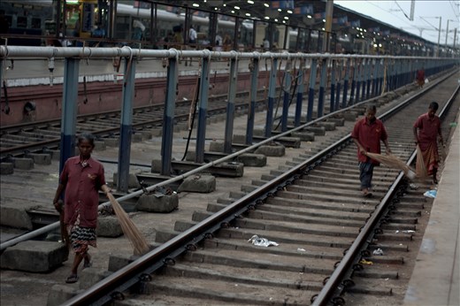 On Indian trains, the window is often seen as a trash bin, and the open-chute train toilets drop sewage directly onto the speeding tracks below. The result is thousands of miles of sewage-covered rails, with fields of paper and plastic on either side of the track. 

Here, at a station near Mysore, women with straw hand-brooms sweep the littered rails.
