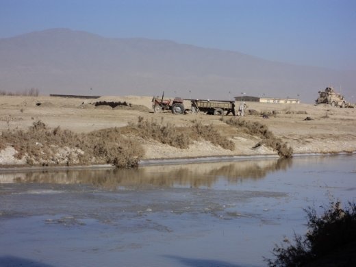 Afghan farmers trying to set free their sunken trailer near the Khandaq River.