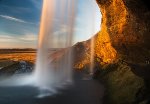 the brilliant orange sunset illuminates the frigid waters crashing into the pool bellow
