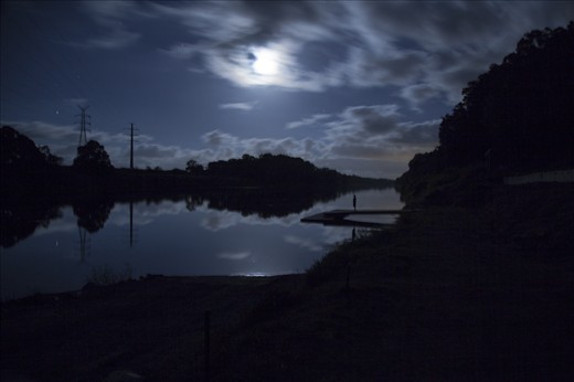 “Pioneer Silhouette” Sitting outside on a balmy North Queensland night, the full moon lit up the sky. I drove to the Pioneer River and parked on the boat ramp, opened my sunroof and put the camera on 20 second exposure.  I love the feeling of this photo.  The silhouette of the man on the pontoon, taking in the moment as the moon is embraced by thick clouds and a star twinkles on the water.