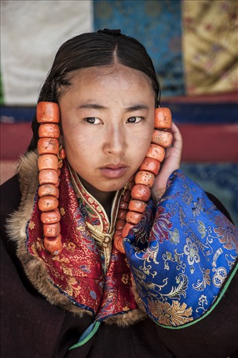A young girl supports the coral beads from pulling on her hair as she waits to parade, for the best part of three days, in the Lurol Festival.
