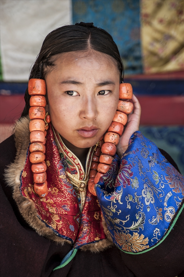 A young girl supports the coral beads from pulling on her hair as she waits to parade, for the best part of three days, in the Lurol Festival.
