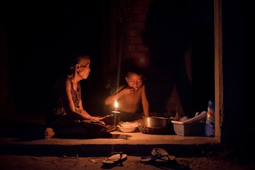 With out access to electricity the evening meal is shared around a kerosene lamp.