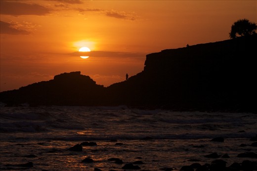 A hot summer sun rises over Fingal headland to bathe the coast in warmth. 
