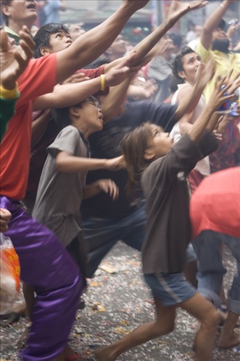 people of different ages racing and hoping catch some blessings thrown by store owners after a lion dance performance