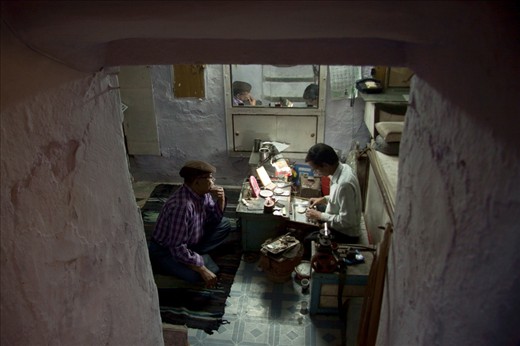 Look inside – A young man working together with and elderly in a small basement space.