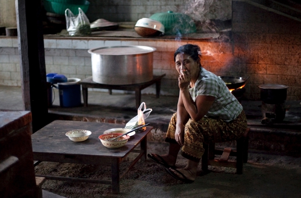 Tea break: a woman takes a break from arduous kitchen duties inside the dark confines of the Shwe Gu monastery.