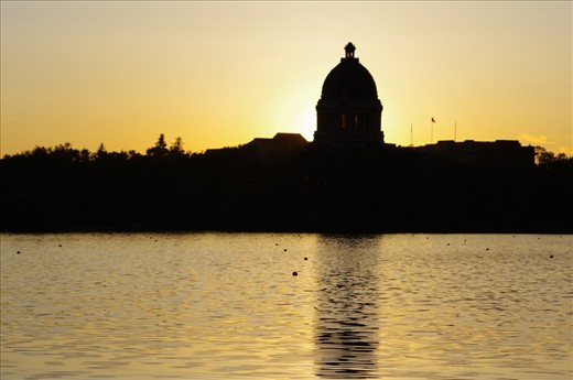 The sun sets, creating a warm mood amidst the cool breeze of the lazy afternoon.  The grandeur of the legislative building casts its shadow.