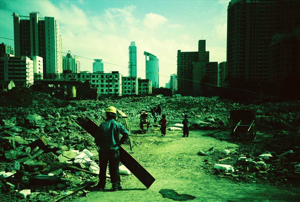 A worker and kids on a demolition site with the future to come on the horizon. Right in the heart of the cities in China you can find these huge demolition sites. Playground for some, opportunities or regrets for others. Probably none of the people on this photo will ever be able to afford to live on  what is going to be built here.
(Analog photo)