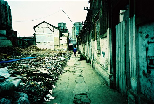 A worker walks through the ruins of a once thriving community. He is actually living in one of the houses at the back. Indeed these houses are still up in order to be used as 