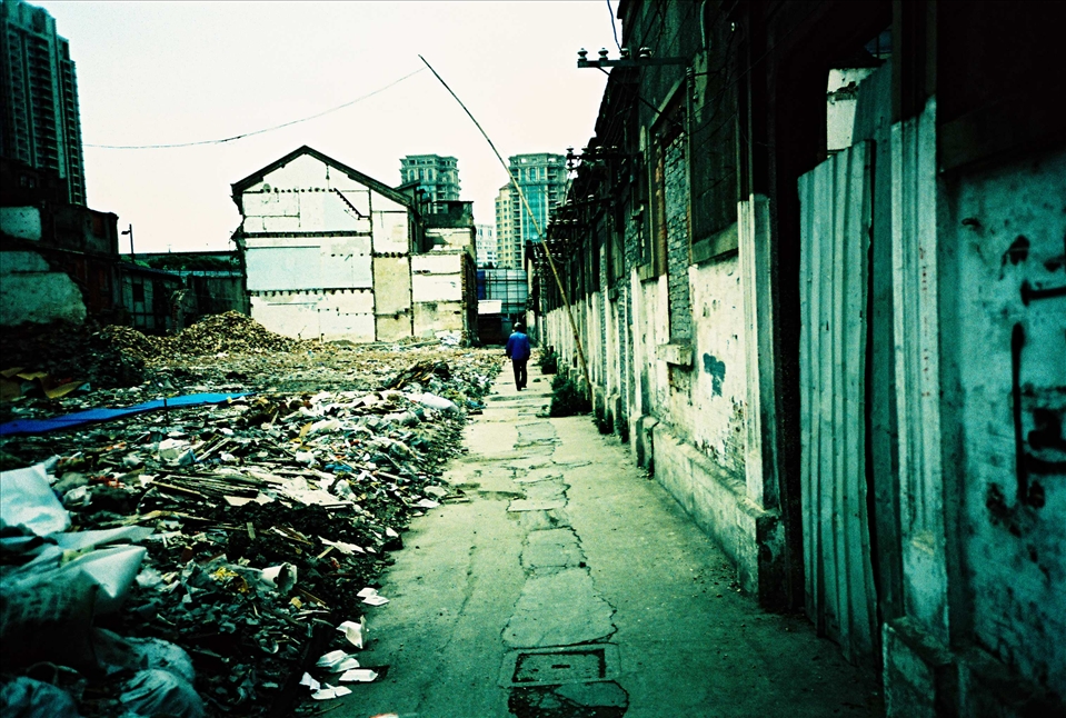 A worker walks through the ruins of a once thriving community. He is actually living in one of the houses at the back. Indeed these houses are still up in order to be used as 