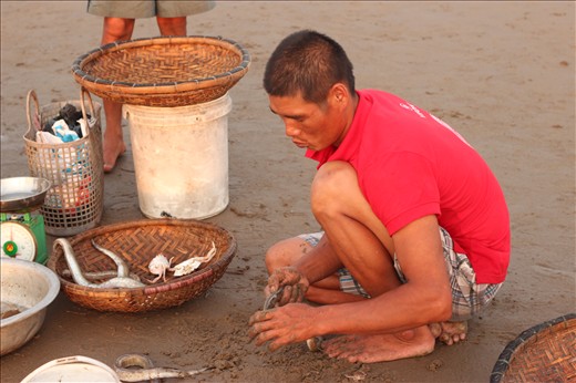 This fisherman is still up and try to earn money by helping to clean the fish.